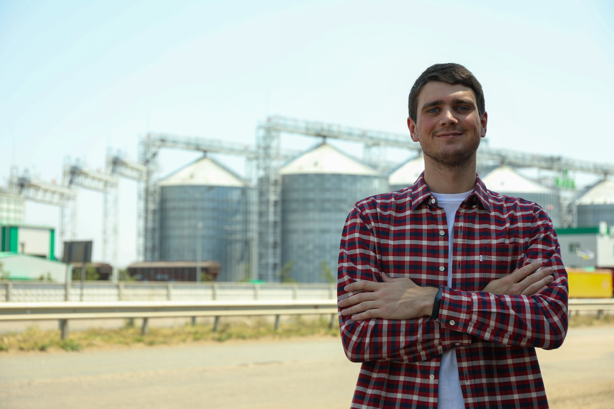 Young man against grain silos. Agriculture business